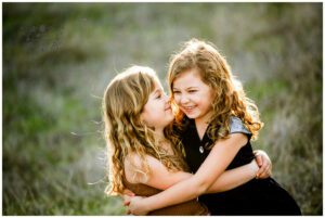 twin girls hug in a california field