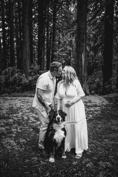 pregnant woman and husband in redwoods with dog