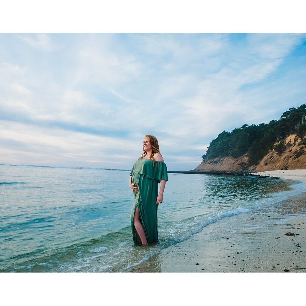 woman in green dress stands in the water in half moon bay