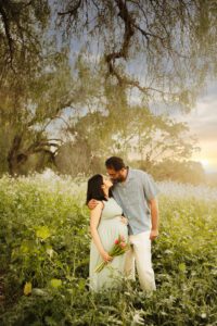 couple kissing in wildflower fields during maternity photo shoot