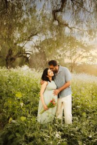 couple kissing in wildflower fields during maternity photo session