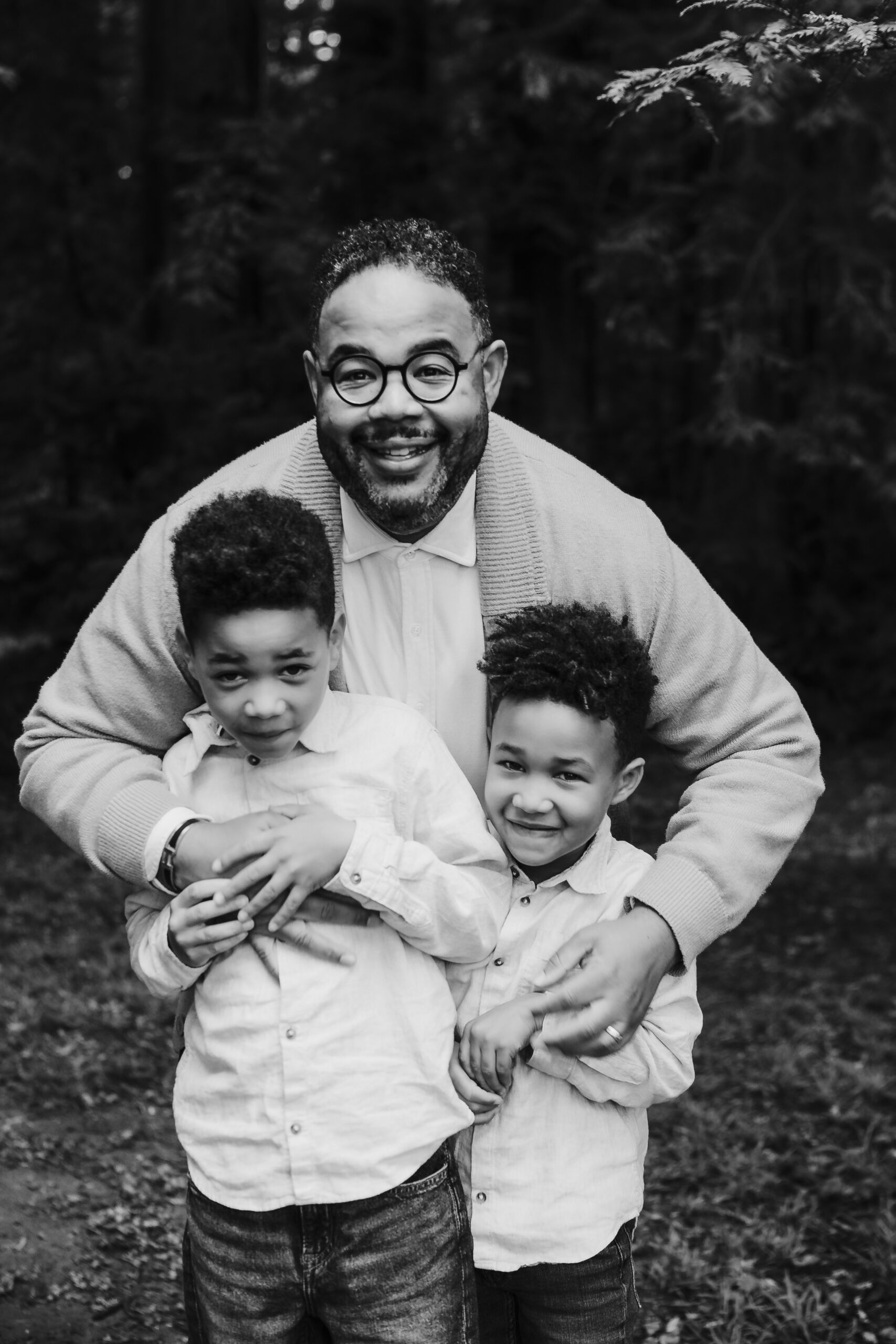 St. Louis family photographer, black and white photo of a smiling father hugging his two young sons outdoors