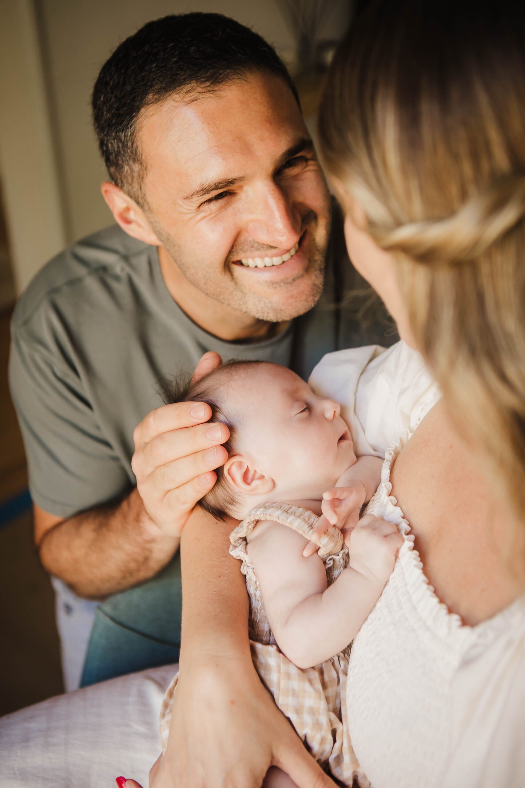 St. Louis newborn photographer, parents smiling at each other while holding their newborn daughter