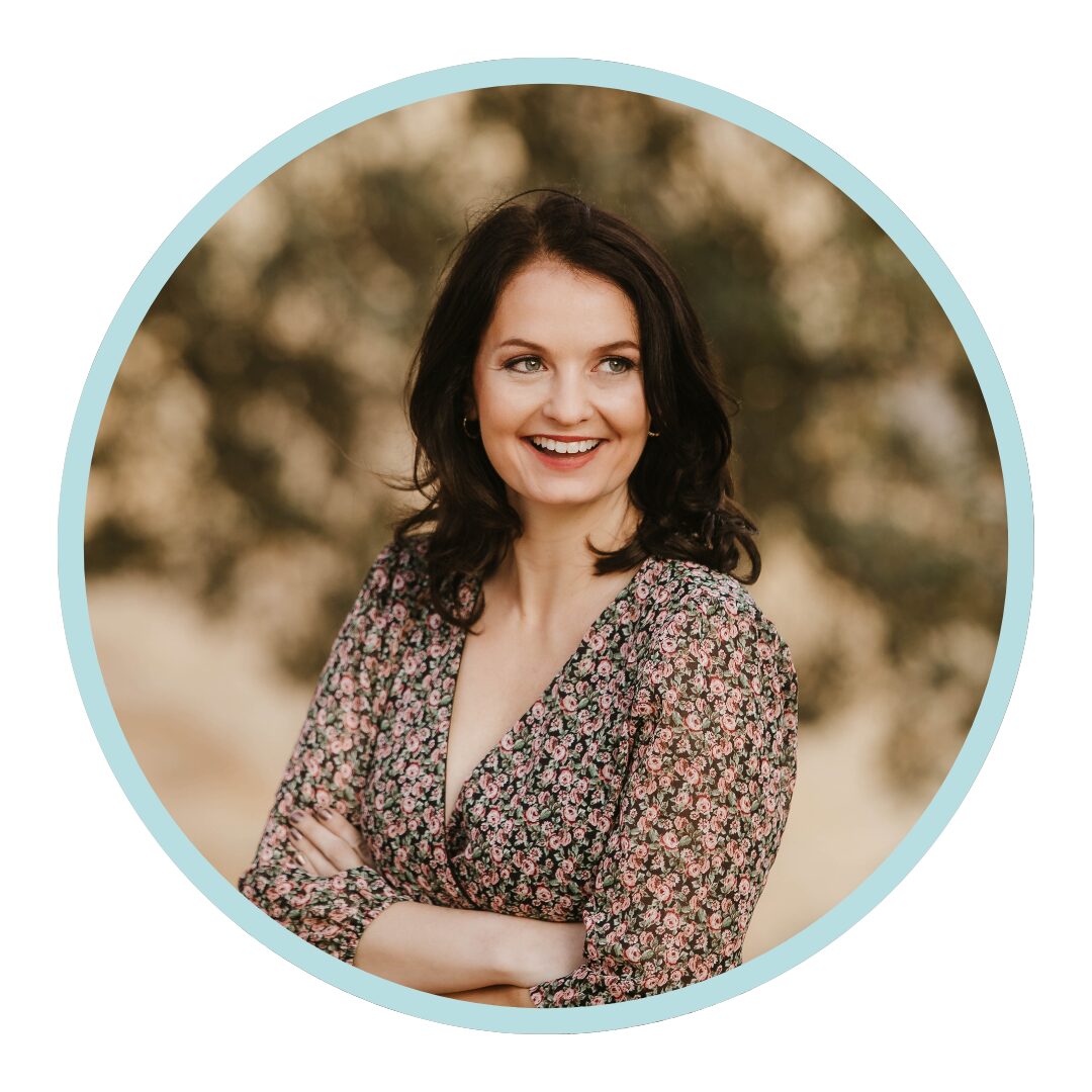 Portrait of a smiling woman with dark hair wearing a floral dress, shown in a round frame with a light blue border