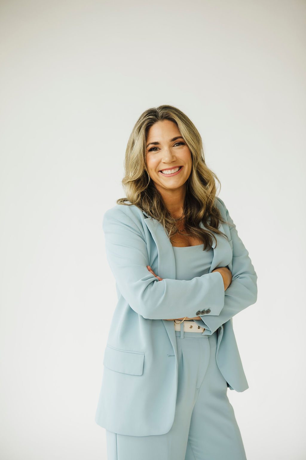 Businesswoman in a light blue suit smiling for a professional headshot in a St. Louis studio
