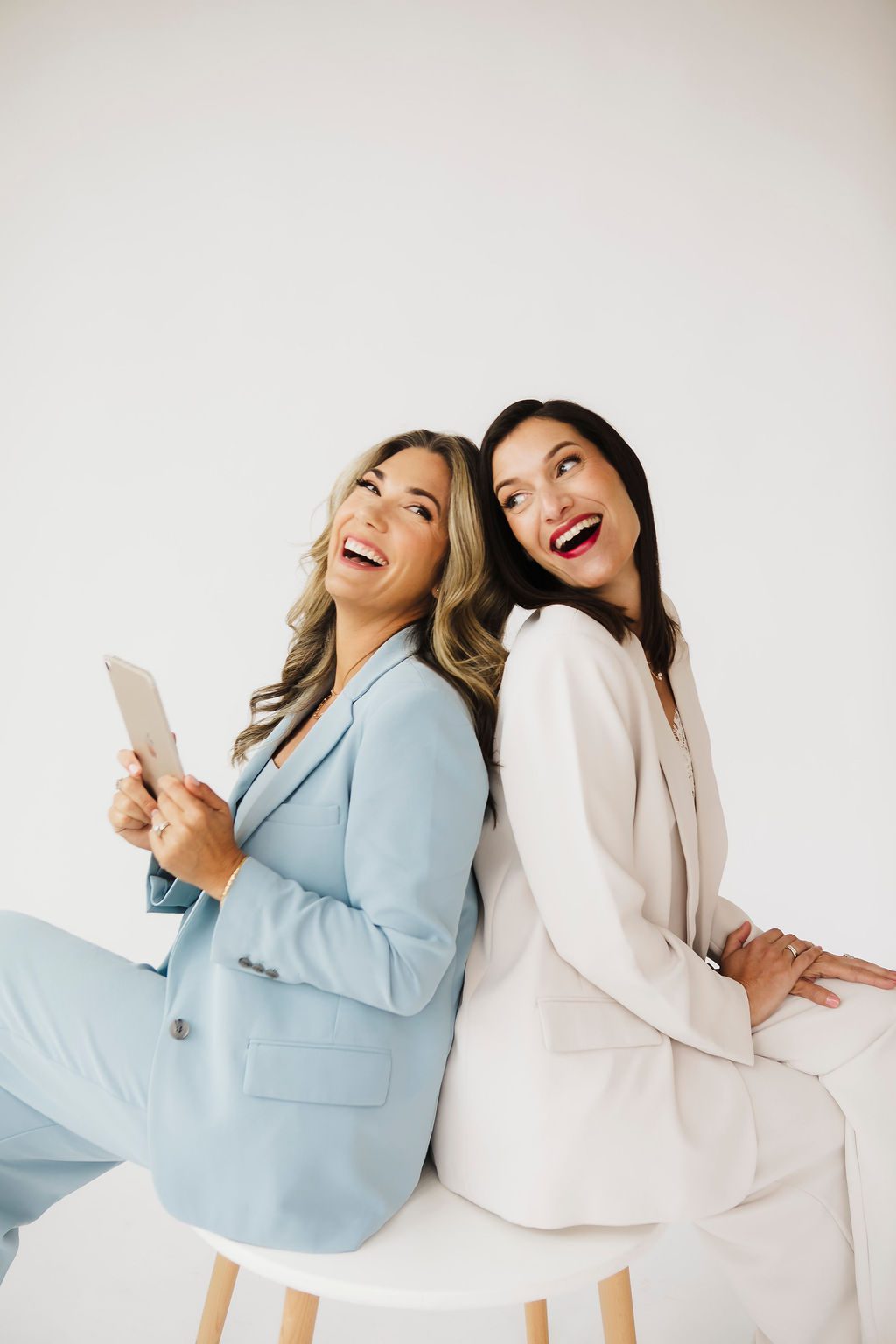 Two businesswomen laughing back to back during a candid St. Louis team branding session