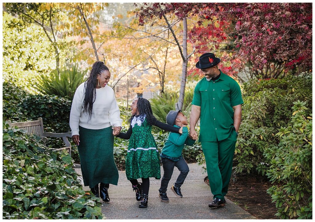 family hold hands as they walk through piedmont park in piedmont ca