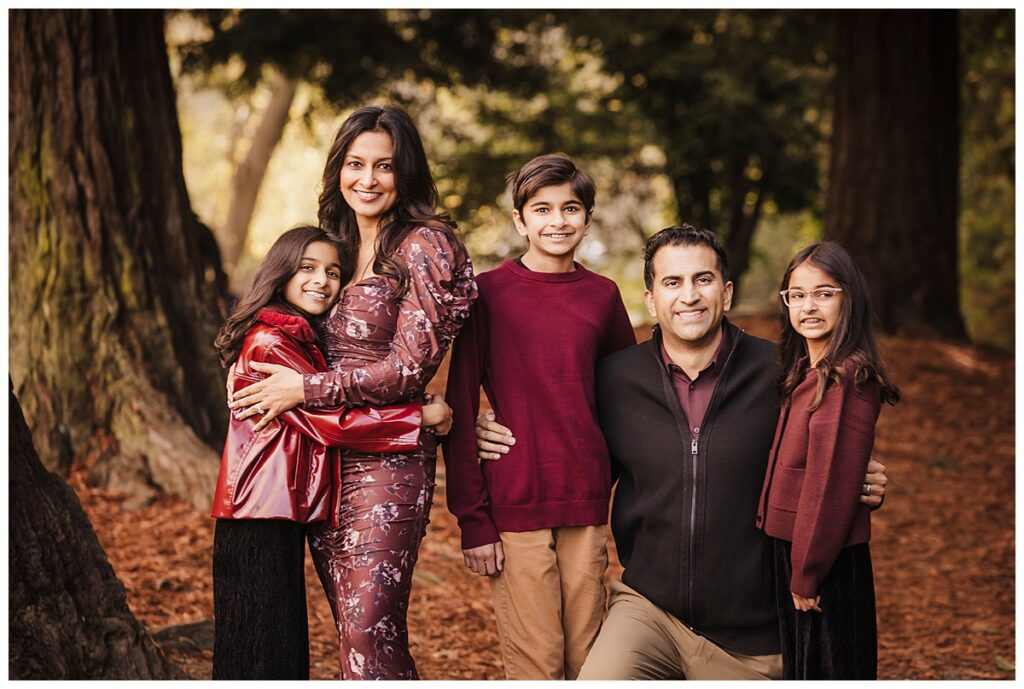 family of five pose for photos at lake temescal in oakland amongst the redwood trees